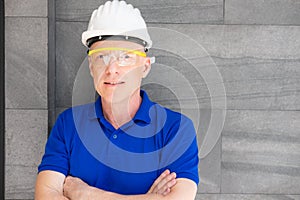 Selective focus at face of Caucasian foreman at building construction site, wearing protective hat and safety equipment while