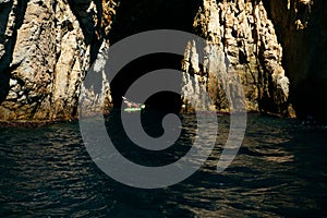 Selective focus - father and son rowing in a canoe to enter a natural cave in the Mediterranean Sea photo