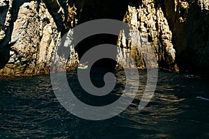 Selective focus - father and son rowing in a canoe to enter a natural cave in the Mediterranean Sea photo