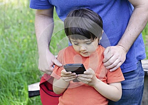 Selective focus father teaching his son using smart phone, Crop shot Dadplaying game with his little boy in the park, Child lookin