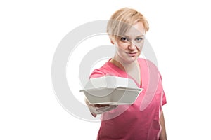 Selective focus of female nurse wearing pink scrubs handing lunchbox