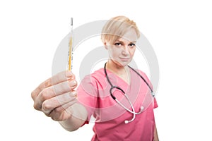 Selective focus female nurse wearing pink scrubs showing thermometer