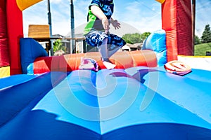 Selective focus on foreword edge of a bouncy house with blurred children playing in the background