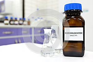 Selective focus of formaldehyde or formalin in brown amber glass bottle inside a laboratory.