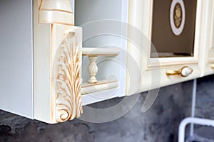 Selective focus fragment of beige wooden cabinetry kitchen carved detail. Carved decorative detail. Wooden pilasters