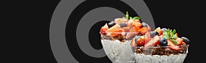 Selective focus of fresh granola with berries and chia seeds isolated on black, panoramic shot
