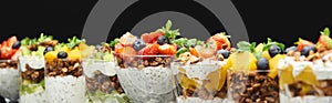 Selective focus of fresh granola with fresh fruits and berries isolated on black, panoramic shot