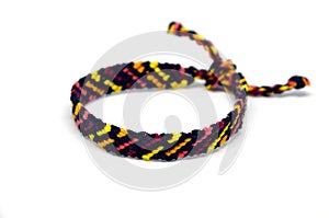 Selective focus of front side of the unisex woven friendship bracelet with ties. Handmade of multi-colored thread. Isolated on whi