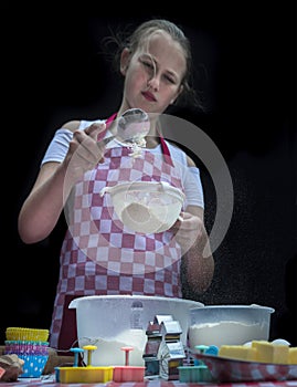 Selective focus. Girl  sifting flour adding baking ingredients. Home bakery