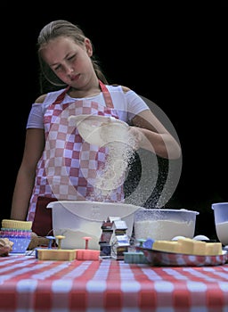 Selective focus. Girl  sifting flour adding baking ingredients. Home bakery