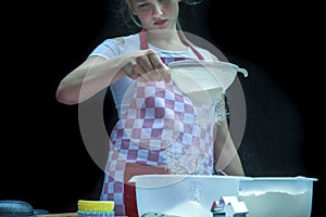 Selective focus. Girl  sifting flour adding baking ingredients. Home bakery