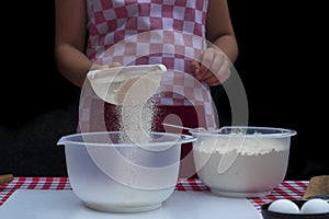 Selective focus. Girl  sifting flour adding baking ingredients. Home bakery