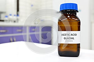 Selective focus of glacial Acetic acid solution in brown amber bottle. Blur white laboratory backdrop with copy space.