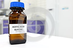 Selective focus of glacial Acetic acid solution in brown amber bottle. Blur white laboratory backdrop with copy space.