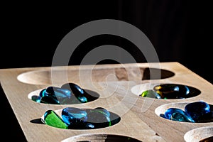 Selective focus on glass beads on a wooden mancala board