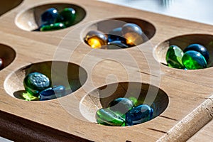 Selective focus on glass beads on a wooden mancala board