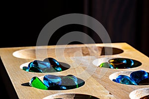 Selective focus on glass beads on a wooden mancala board