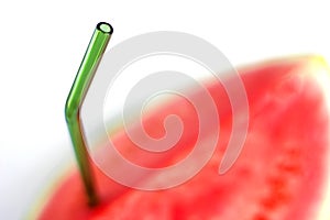 Selective focus on glass green eco reusable straw in Fresh red watermelon on white background. fresh fruits and natural juices.