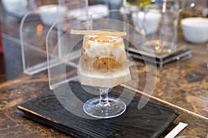 Selective focus, glass of Iced coffee with milk, caramel syrup in coffee shop. cold latte coffee in cup on wooden table in cafe