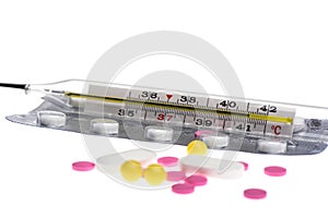 Selective focus. Glass mercury thermometer on a blister with pills isolated on a white background