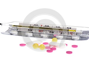 Selective focus. Glass mercury thermometer on a blister with pills isolated on a white background