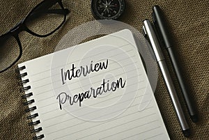 Selective focus of glasses,compass,pen and notebook written with Interview Preparation on rugs background