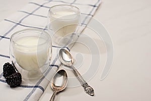 Selective focus of glasses of homemade yogurt with blackberries on cloth near teaspoons