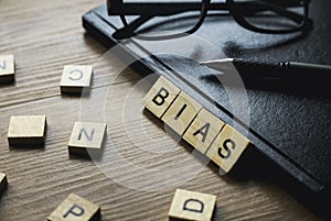 Selective focus of glasses, pen, notebook and wooden alphabet of word Bias