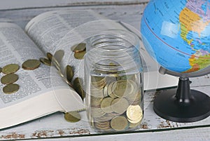 Selective focus of Gold coins on book with globe. Finance and education concept