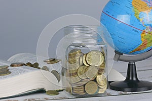 Selective focus of Gold coins on book with globe. Finance and education concept