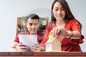 Selective focus of golden coin. Happy Asian couples smiling Because it is profitable from investment And have savings for buying a