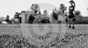 Selective focus on grass with blurred girls softball game in the background