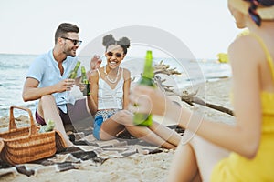 selective focus of group of friends with beer resting on sandy