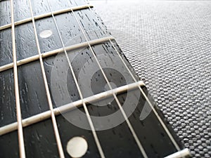 Selective focus guitar fretboard with strings on blurred gray background with copy space. Music concept. Guitar neck texture. Gray