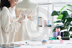 Selective focus on hand of attractive 30s woman fashion designer or dressmaker touching textile fabric texture, work with mannequi