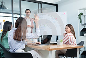 Selective focus on hand of a colleague woman raising hand to ask question during businessman presenting successful ideas or