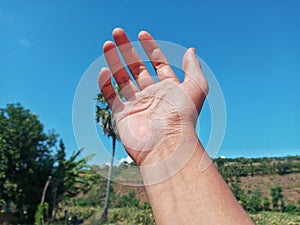 Selective Focus of A Hand Reaching Out Towards the Sky with Blurred Sky Background