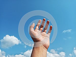 Selective Focus of A Hand Reaching Out Towards the Sky with Blurred Sky Background