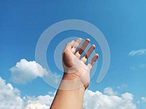 Selective Focus of A Hand Reaching Out Towards the Sky with Blurred Sky Background