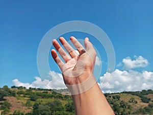 Selective Focus of A Hand Reaching Out Towards the Sky with Blurred Sky Background