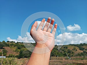 Selective Focus of A Hand Reaching Out Towards the Sky with Blurred Sky Background