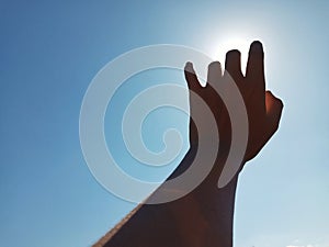 Selective Focus of A Hand Reaching Out Towards the Sky with Sky Background