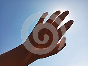 Selective Focus of A Hand Reaching Out Towards the Sky with Sky Background