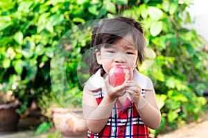 Selective focus, hands have black nail of child girl holding apple for eating healthy. Natural green background.