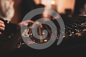 Selective focus of hands mixing music on a professional controller board