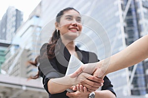 Selective focus on hands of success young Asian business woman and man shaking hands after deal. Partnership concept