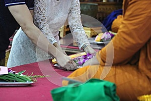 Selective focus on hands of young couple make merit to monks in buddhism temple