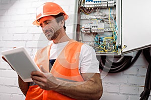 Focus of handsome electrician using digital