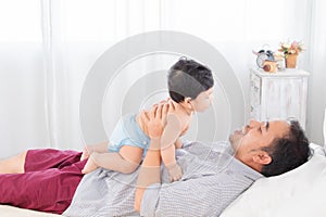 Selective focus happy asian father playing and look into eyes with newborn baby with love and fun on bed. Dad and adorable infant