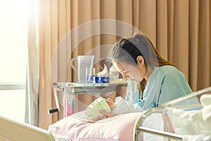 Selective focus of Happy asian mother looking newborn baby boy sleeping in hand at hospital
